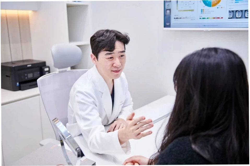 깨끗한 진료실에서 의사가 환자에게 울쎄라 시술 관련 설명을 하는 모습. 환자와의 심도 깊은 상담을 통해 울쎄라 300샷 600샷 차이를 상세히 안내하는 의료 전문가의 모습이다.